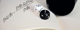 Bayes' theorem hand-written on a notebook. Additionally, two dice are rolled on top of the notebook from a black plastic cup.