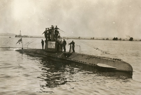 A photo of a Geman U-boat from WWI, half submerged in water with the crew on top