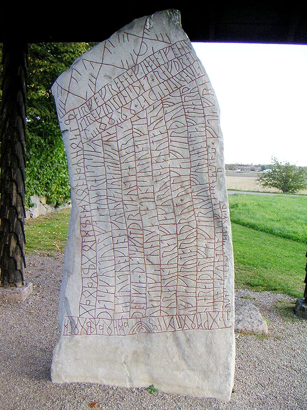A photo of a runestone with old runic cipher in the form of lines and strokes of different size and orientation