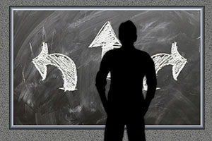 A person standing in front of a blackboard with three arrows pointing in different directions