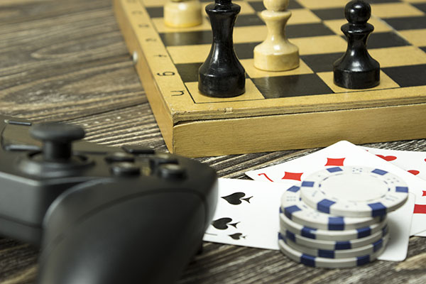 Gamepad, a chess board with figures and playing cards with the chips on the table. Focus on card