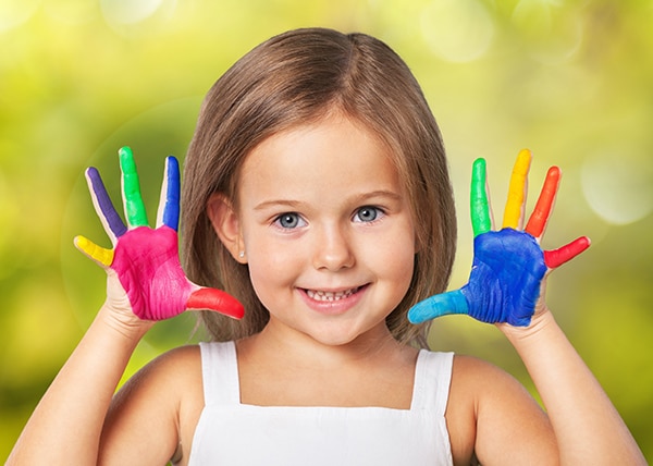 A smiling little girl showing ten painted fingers